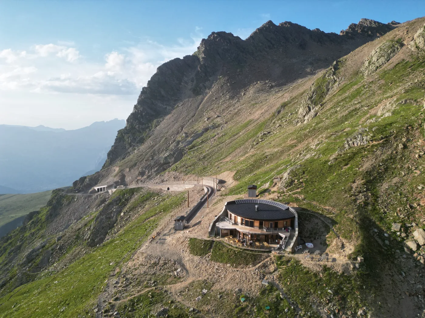 Le Refuge du Nid d'Aigle et sa terrasse, adossés au versant au-dessus du terminus du Tramway du Mont-Blanc